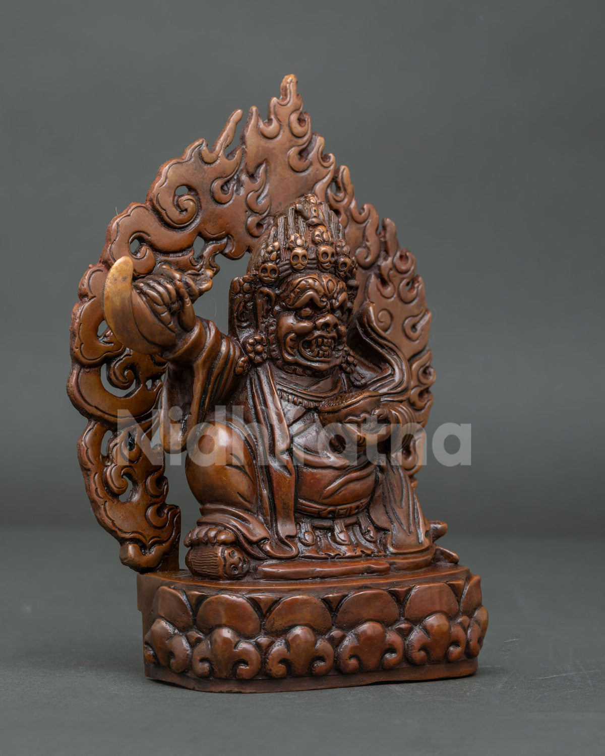 Side view of oxidized copper Tibetan Mahakala Bernagchen statue with kartika knife and skull cup.