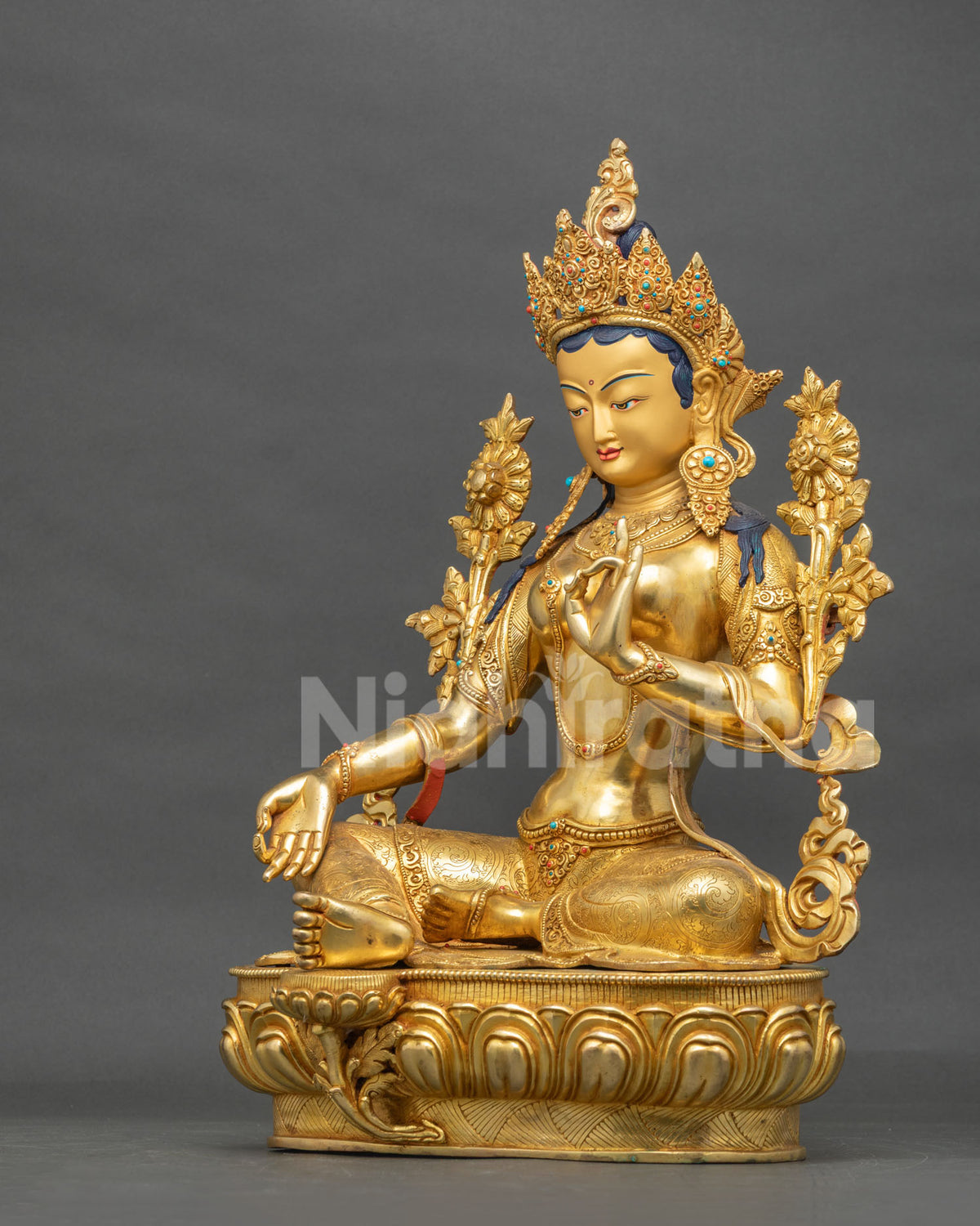Side view of the seated Green Tara copper statue in Varada Mudra with right leg extended on a lotus throne