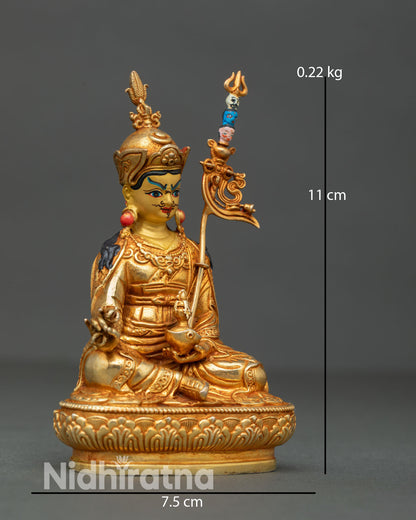 Side view of Tibetan Guru Rinpoche sculpture depicting khatvanga trident staff flowing robes and majestic seated posture on carved lotus throne