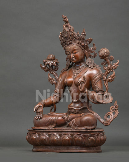 Side view of White Tara statue with elegant robes blooming utpala lotuses and oxidized patina.
