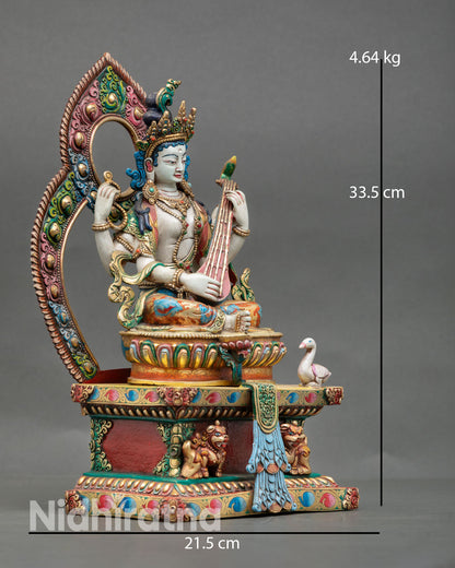 Side view Saraswati seated on lotus throne with snow lion support holding vina Himalayan copper goddess