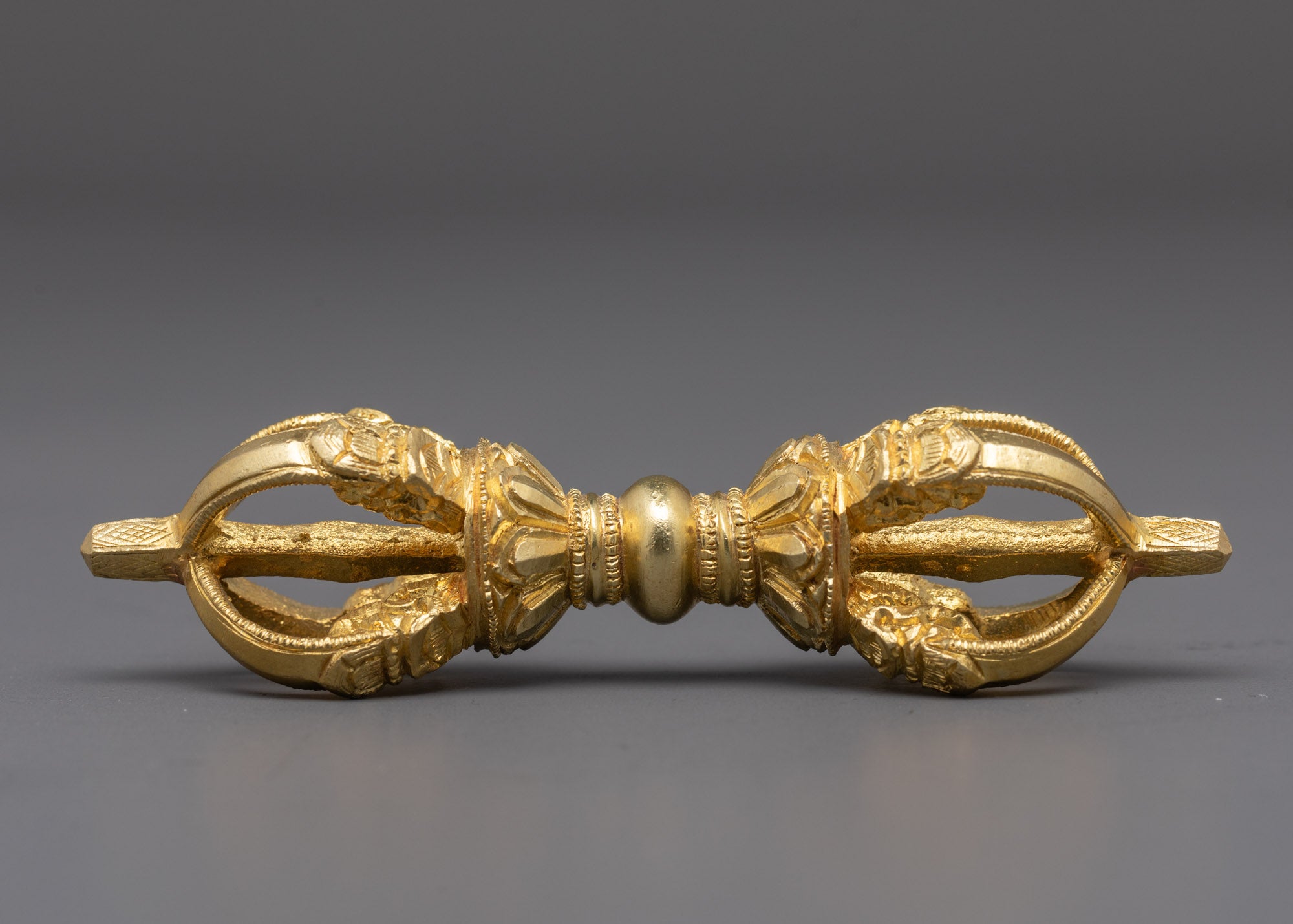 side angle of handcrafted vajra showing intricate gold-plated copper finish
