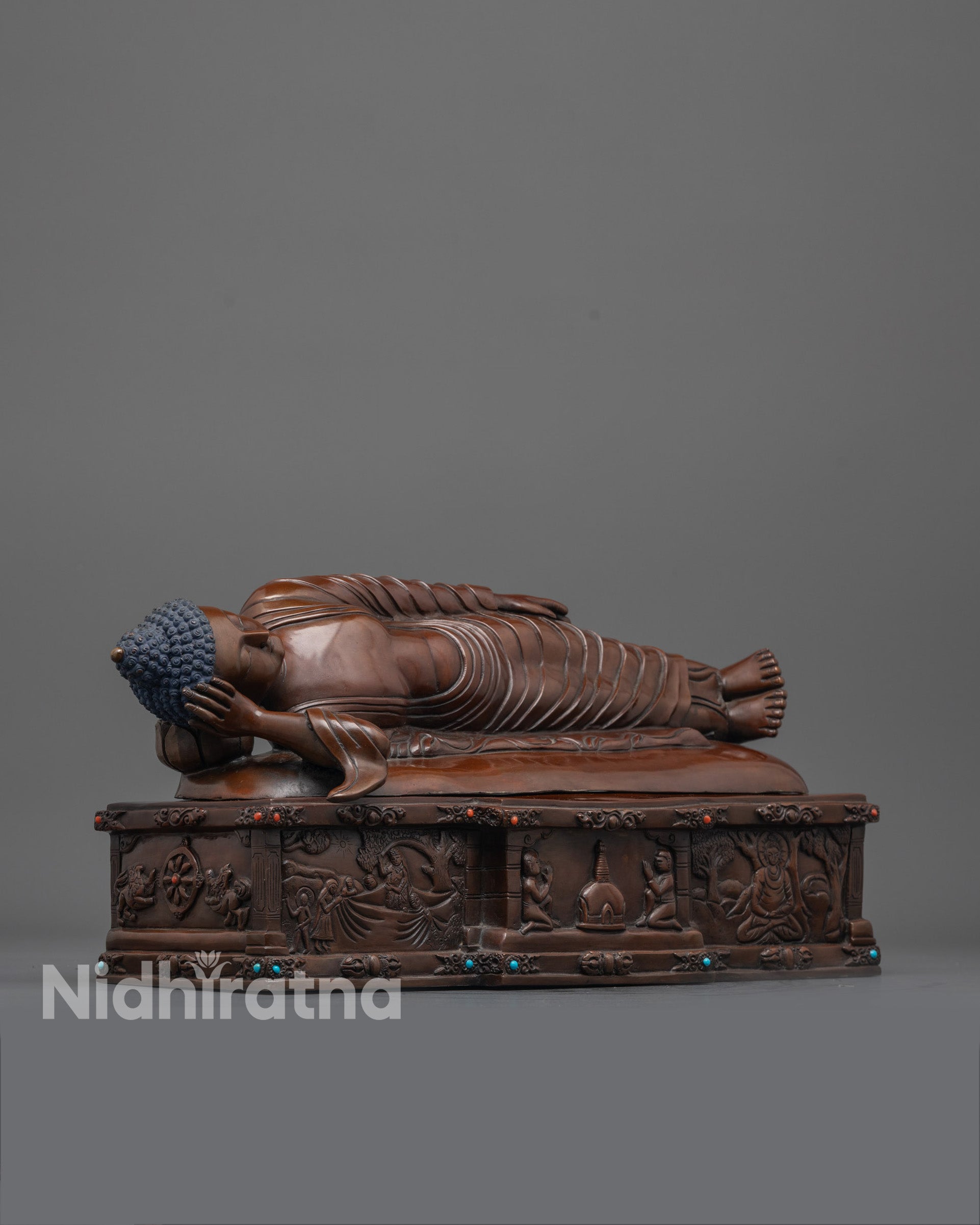 side angle of nirvana buddha on parinirvana bed with carved symbols and semi-precious stones