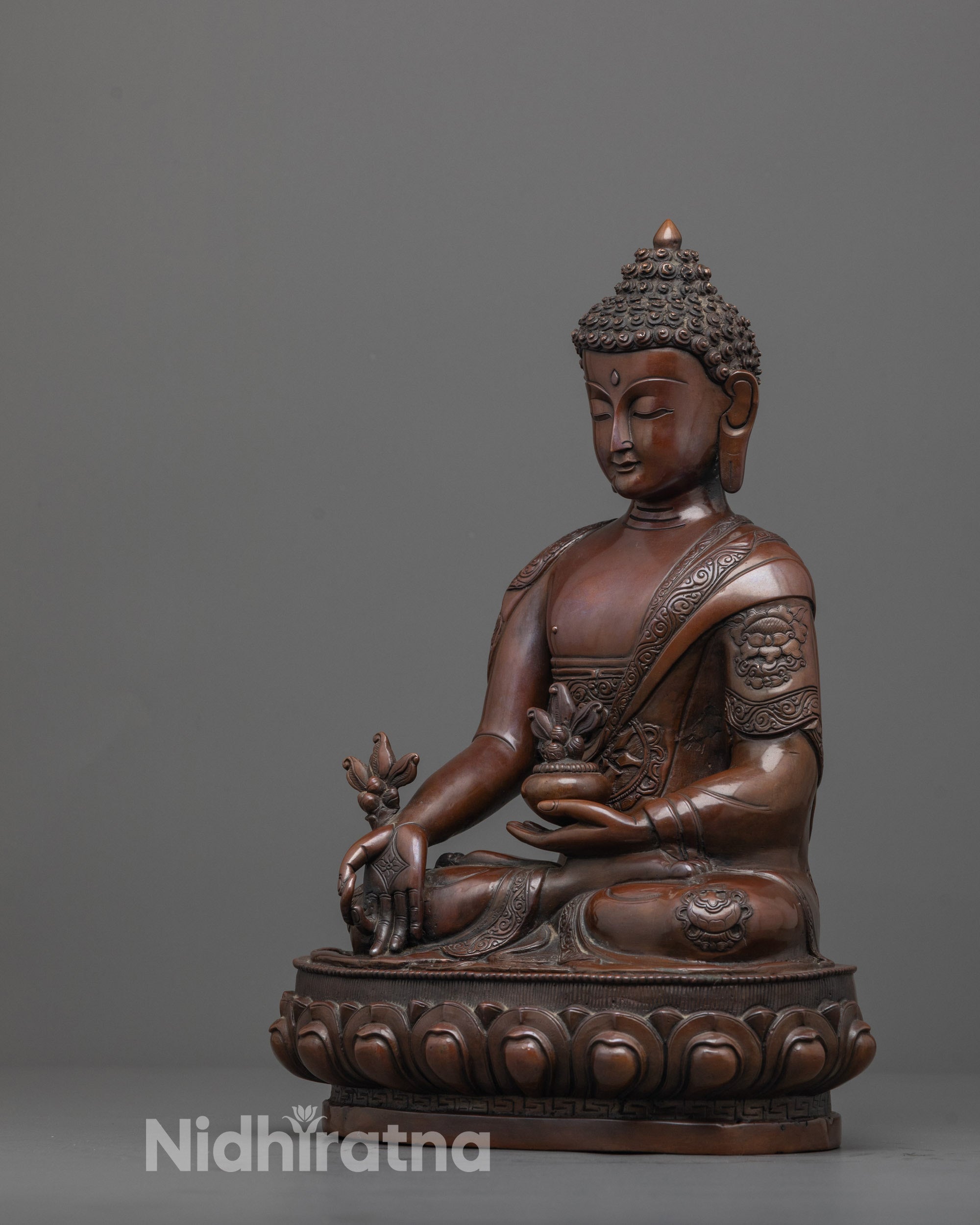 side angle of oxidized bhaisajyaguru statue showing healing symbols on monk's robe