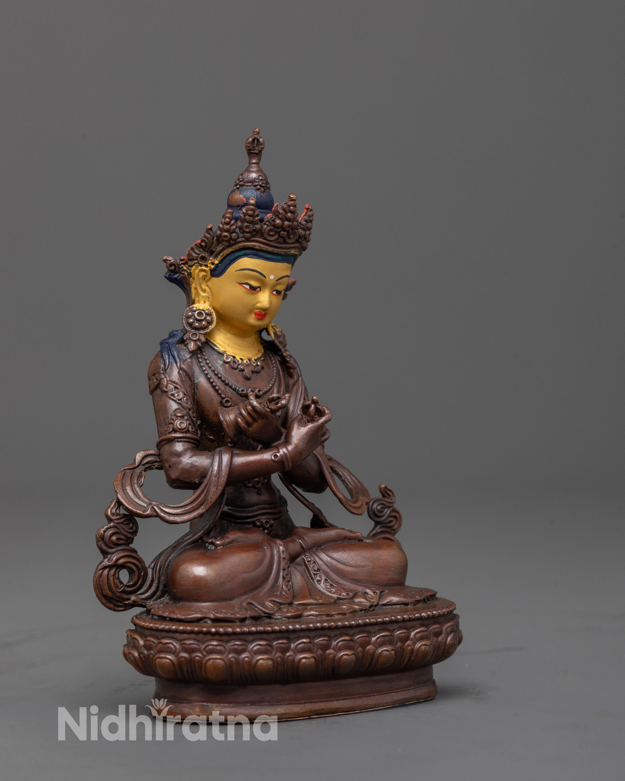 side angle of oxidized vajradhara statue holding vajra and bell
