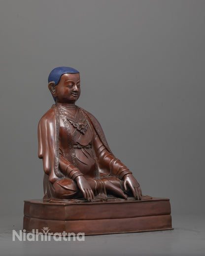 side angle of traditional oxidized Marpha Statue with flowing monk’s robes and seated posture
