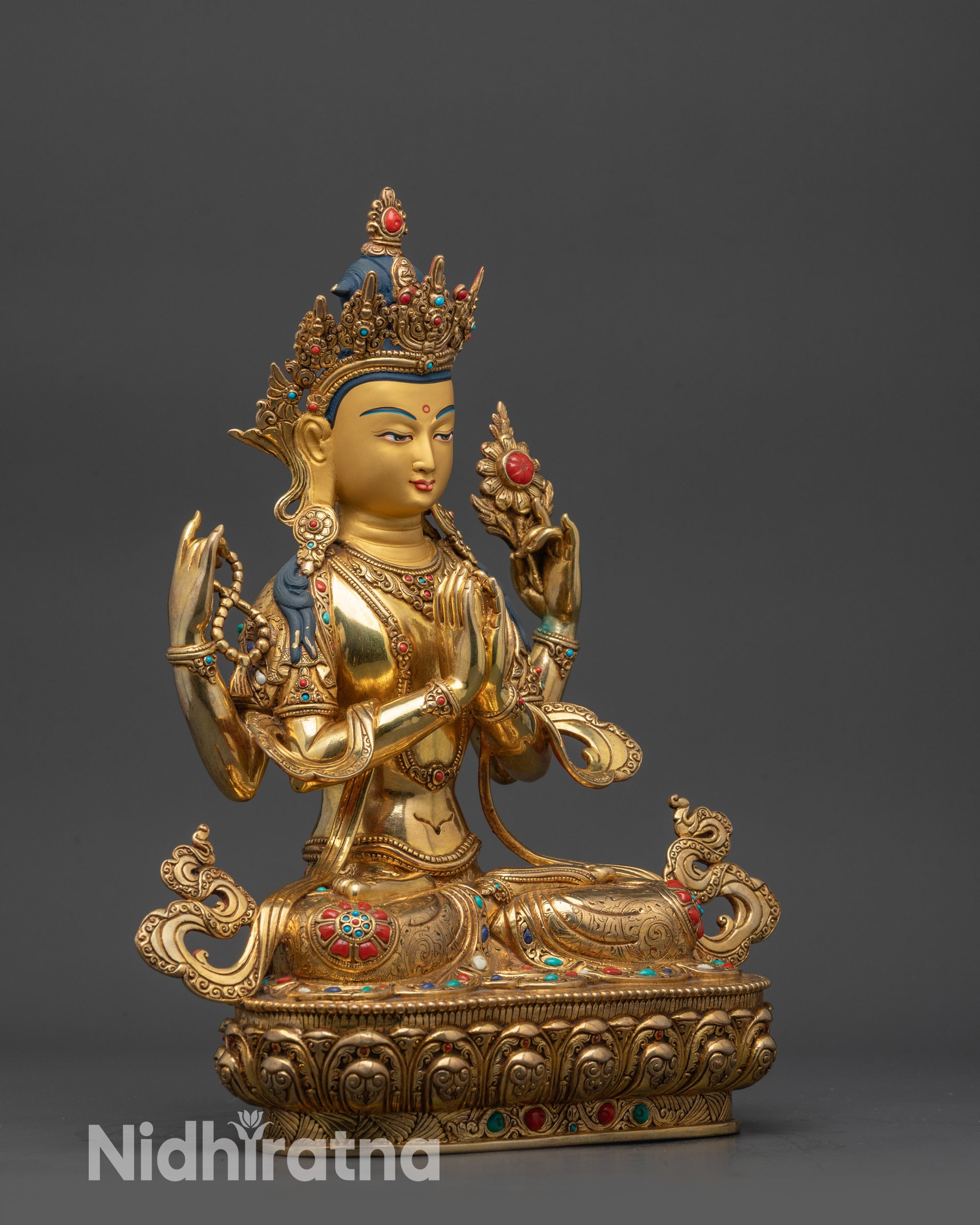 side view Chenrezig statue with flowing robes, four arms, and sacred objects visible