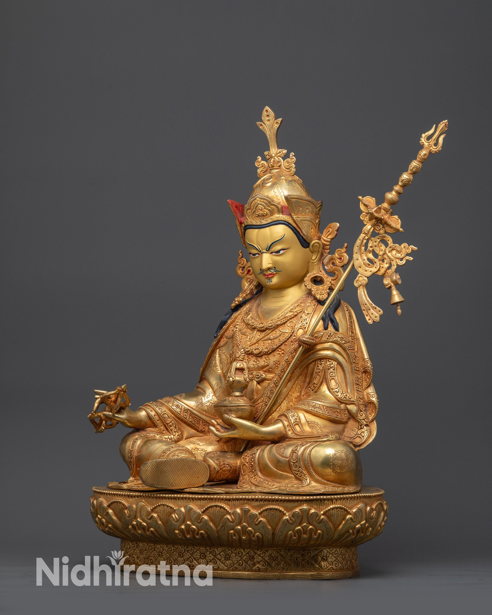 side view Guru Padmasambhava statue holding vajra kapala and khatvanga staff on shoulder