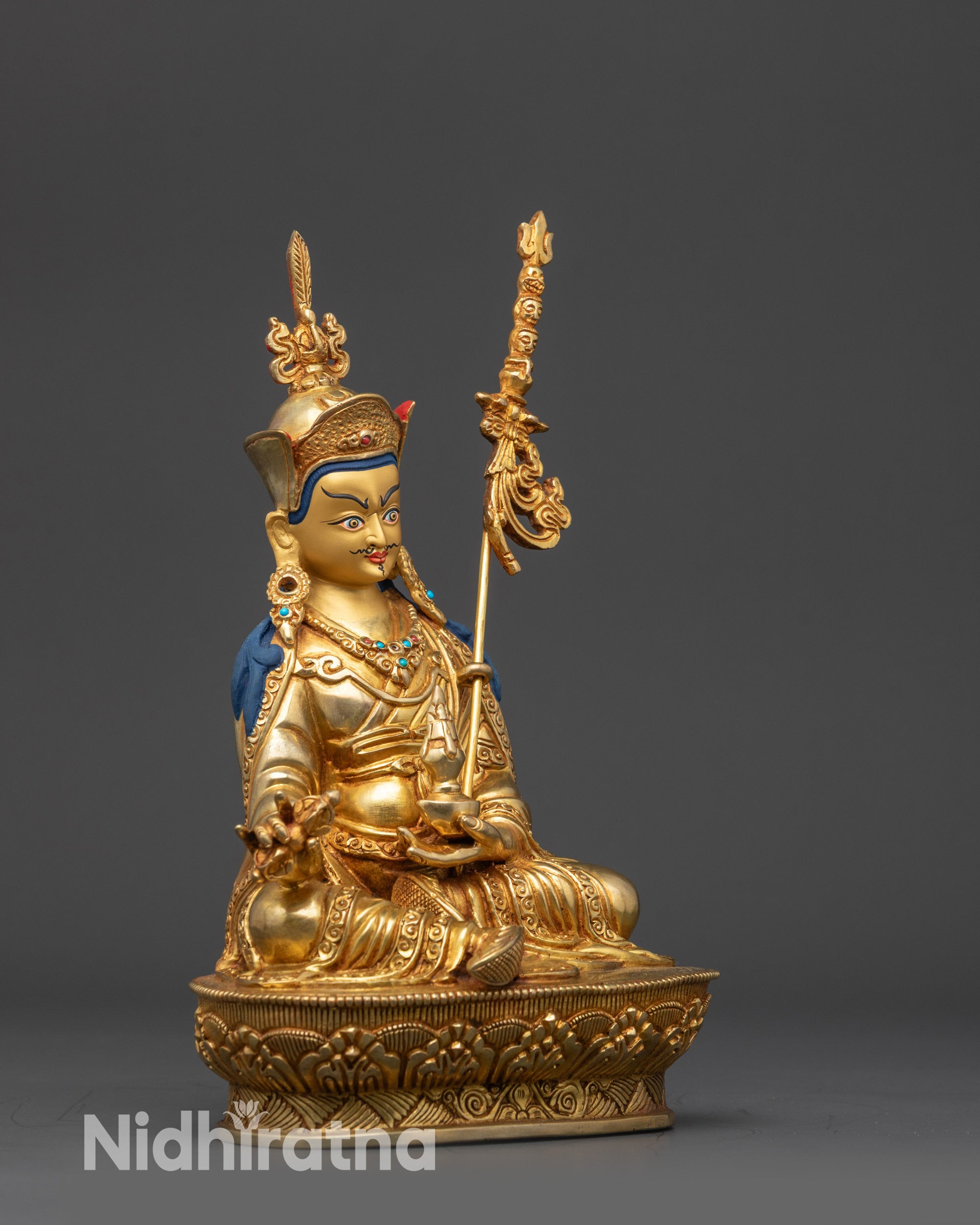 side view Guru Rinpoche statue holding khatvanga trident vajra and kapala on lotus seat