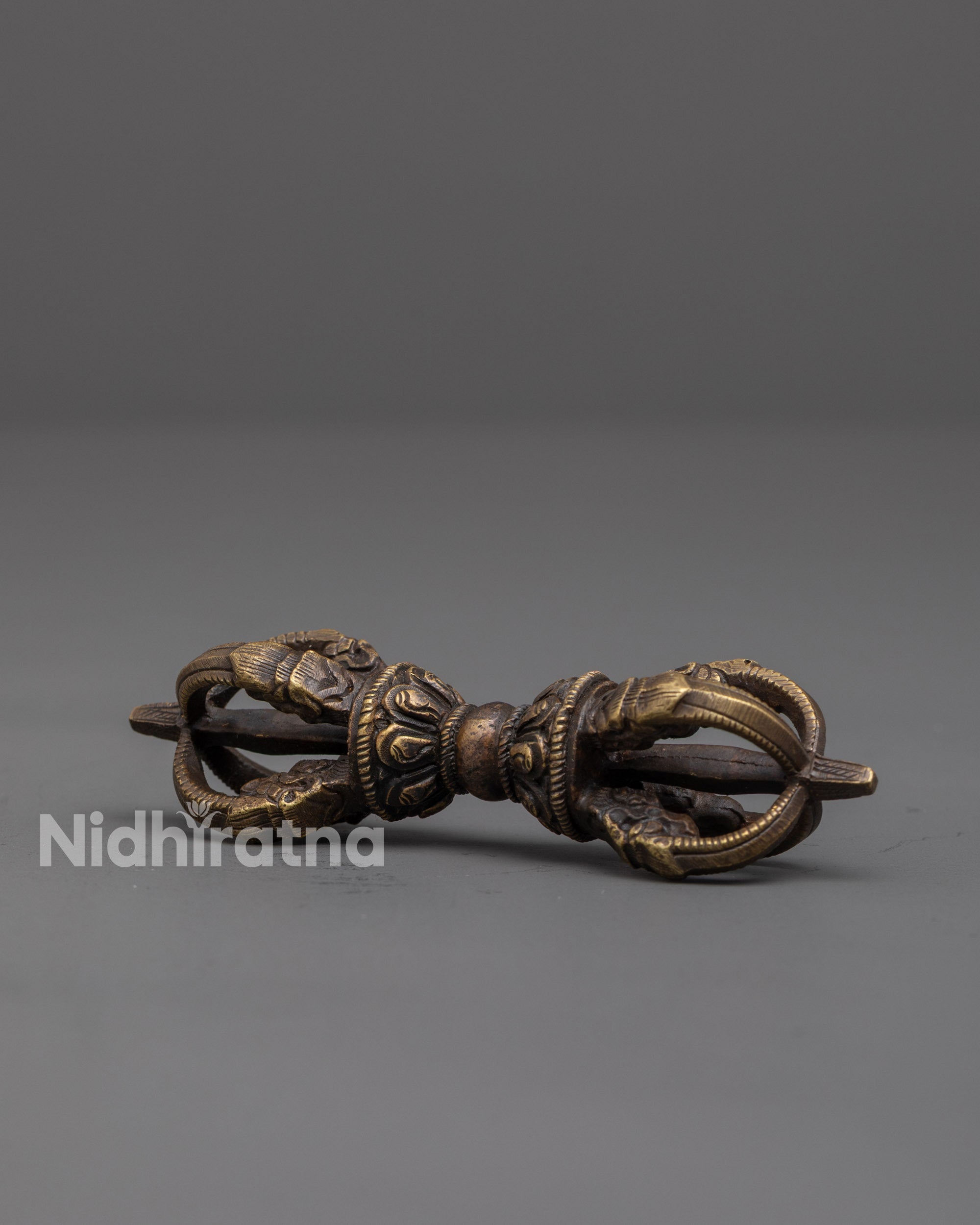 side view of bronze vajra showing carved patterns and sacred ritual details