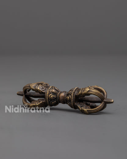 side view of bronze vajra showing carved patterns and sacred ritual details