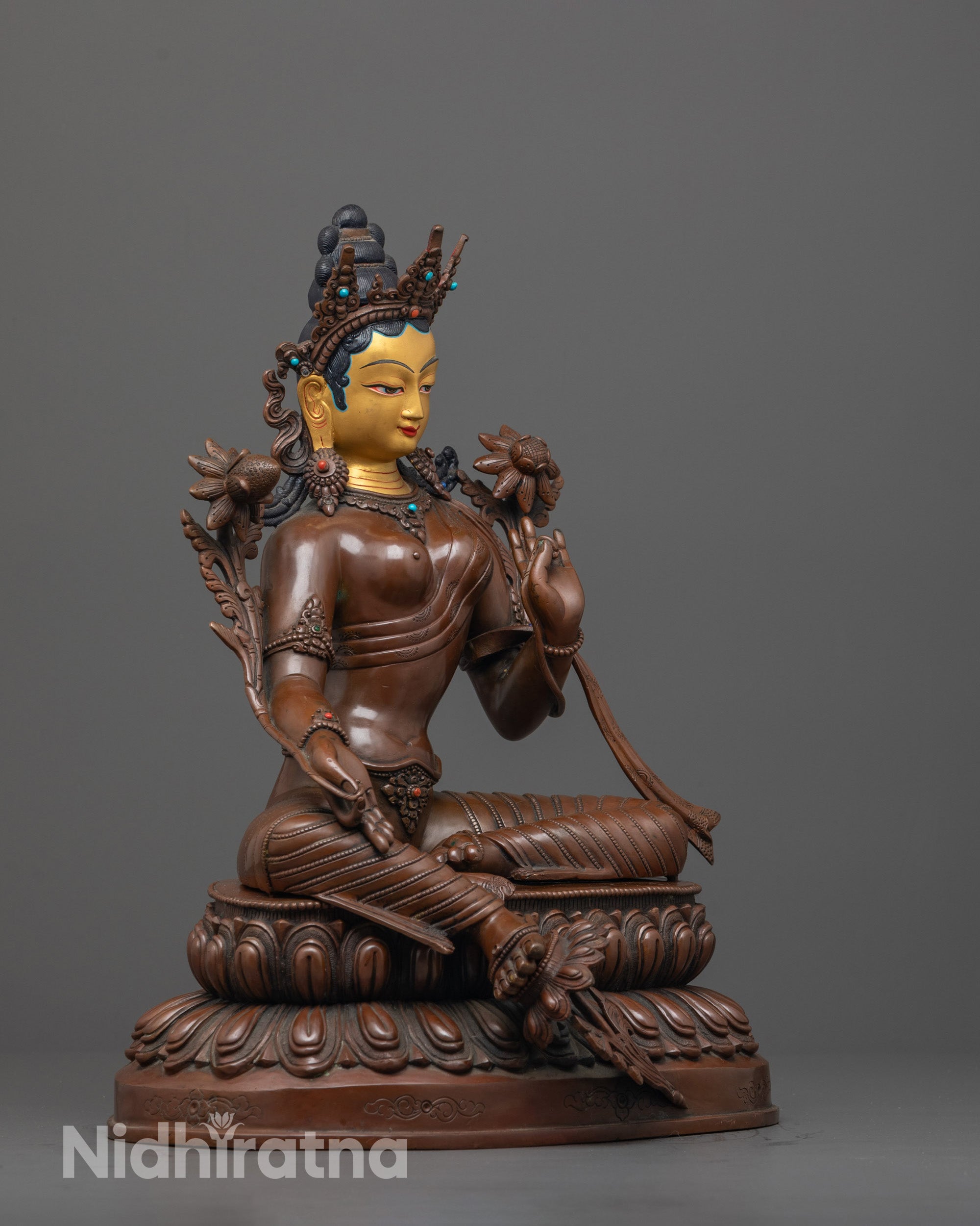 side view of green tara sculpture showing flowing robe and double-layered lotus pedestal