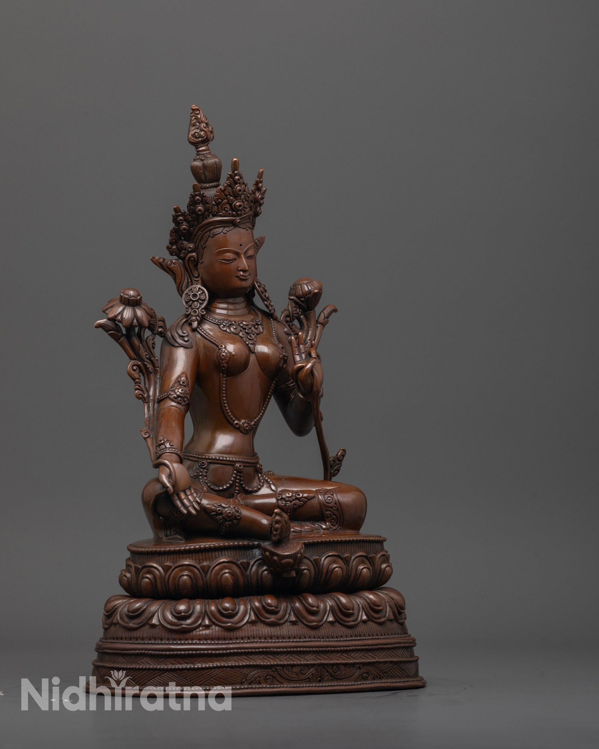 side view of green tara statue in royal ease on double lotus base with oxidized finish