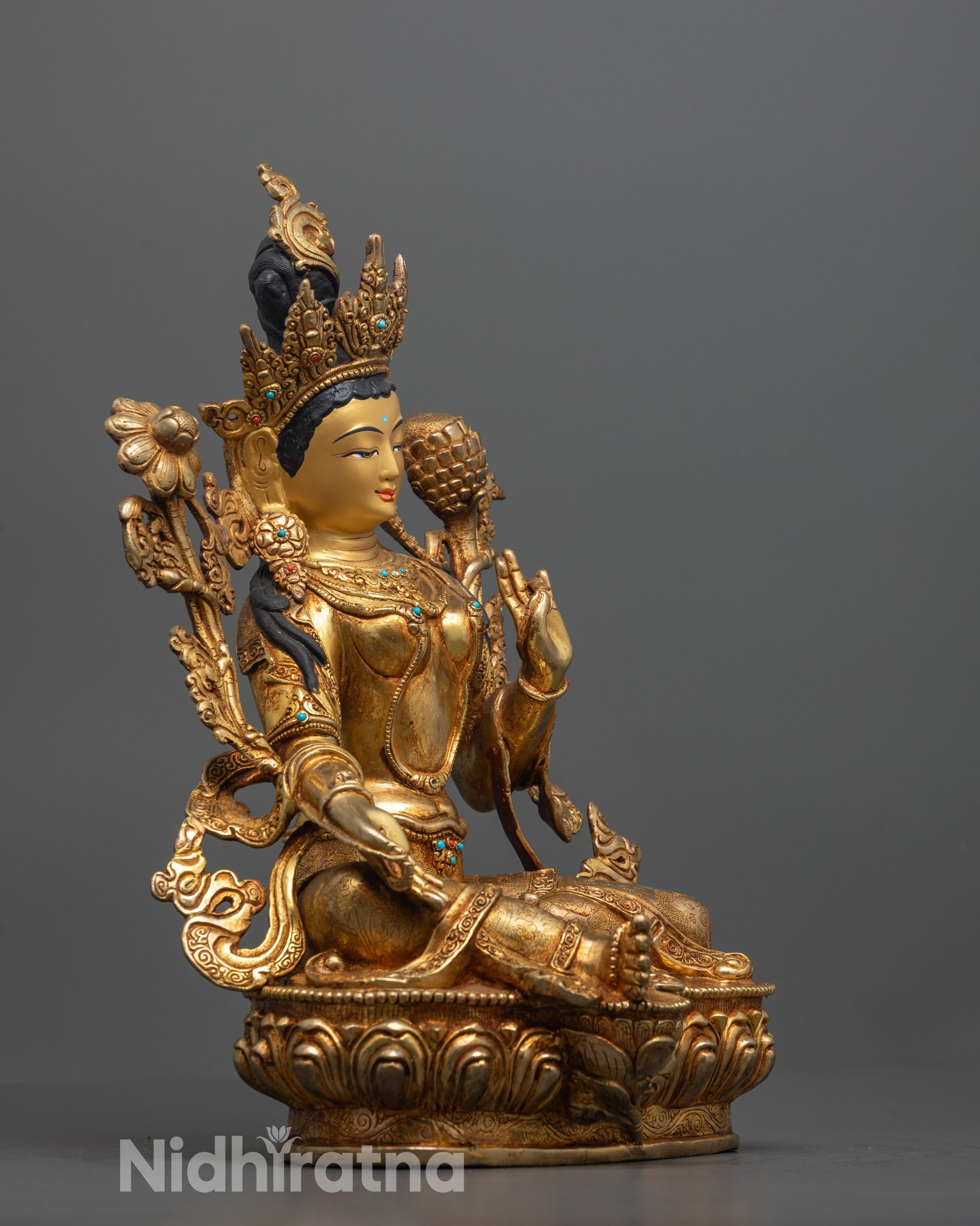 side view of green tara statue with vitarka mudra and utpala flower in graceful pose