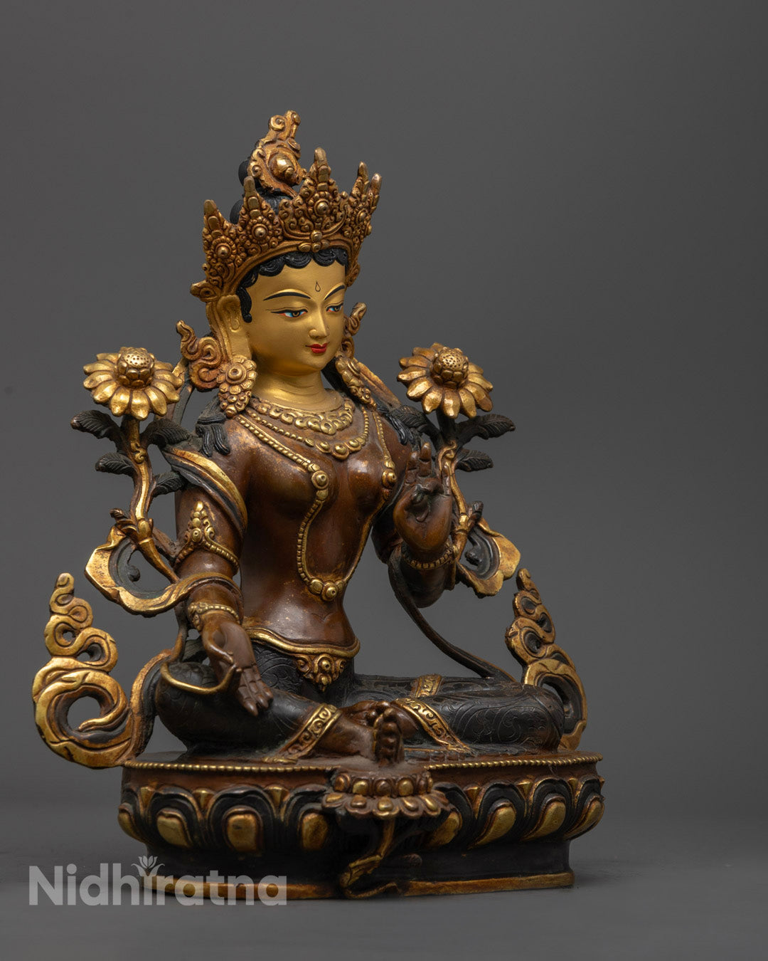 side view of oxidized copper green tara statue holding utpala flower in royal ease pose