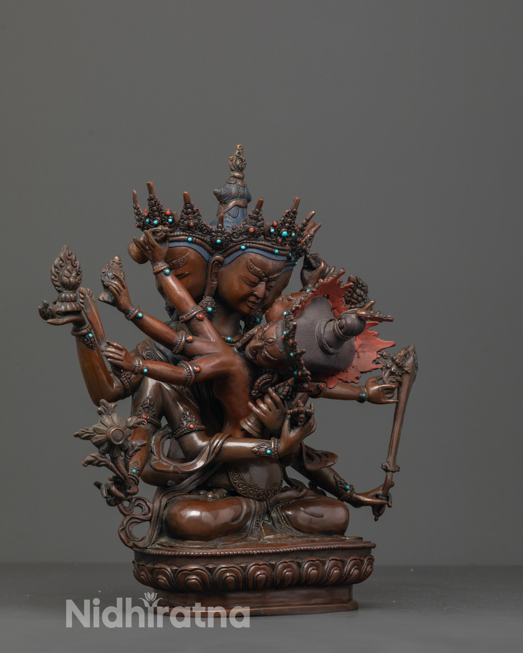 side view of oxidized copper guhysamaja statue seated in union atop lotus base
