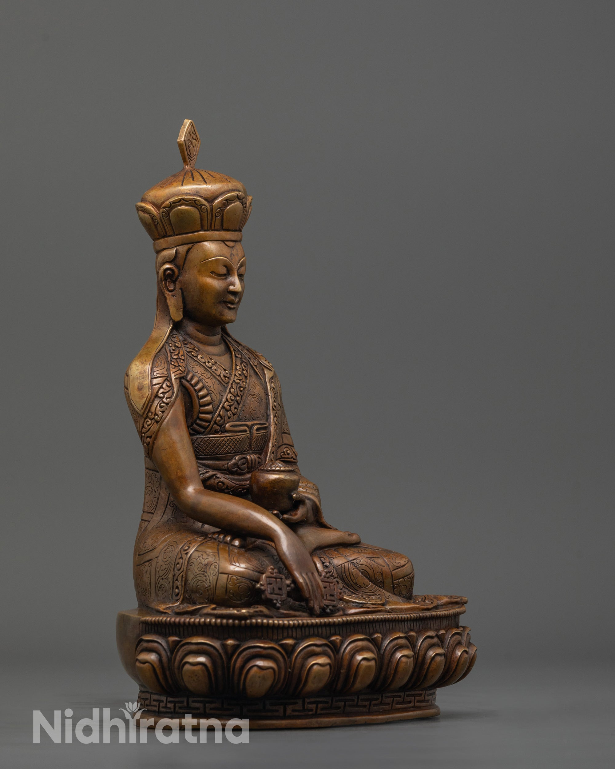 side view of oxidized karmapa statue highlighting robe folds and lotus seat design