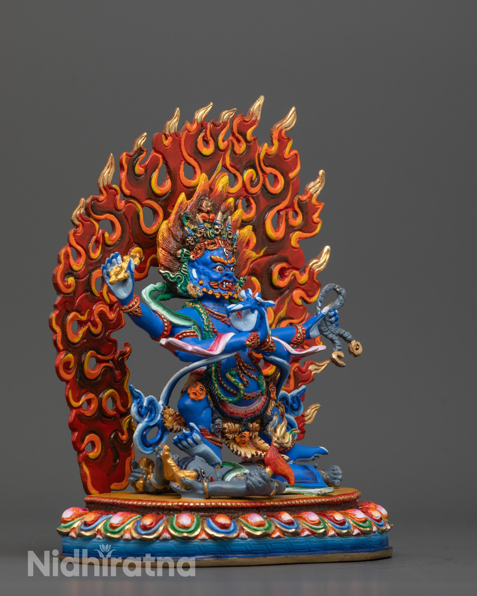 side view of vajrapani statue with subdued deity and multicolored lotus seat