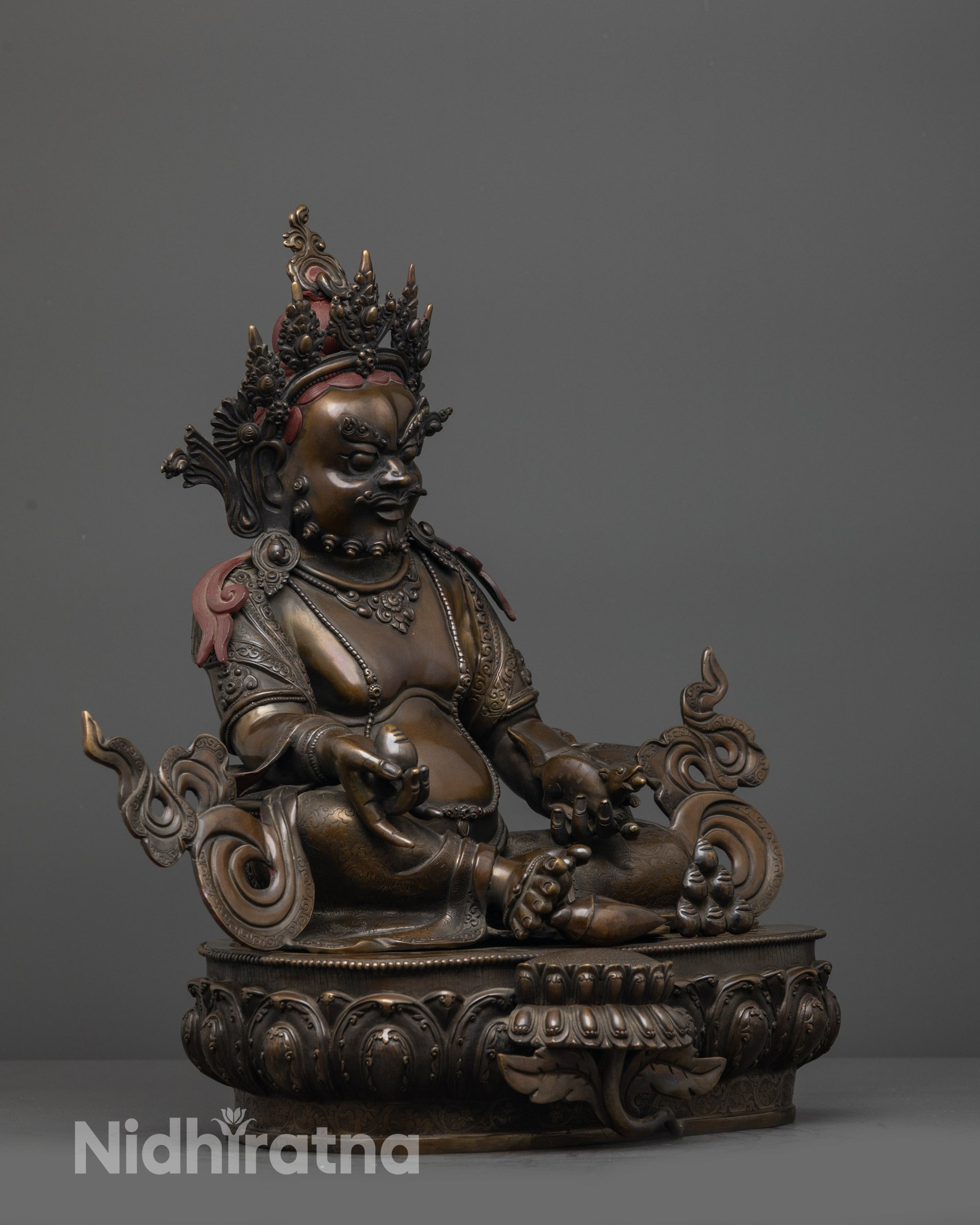 side view oxidized Dzambhala statue seated on moon disc with foot in conch shell
