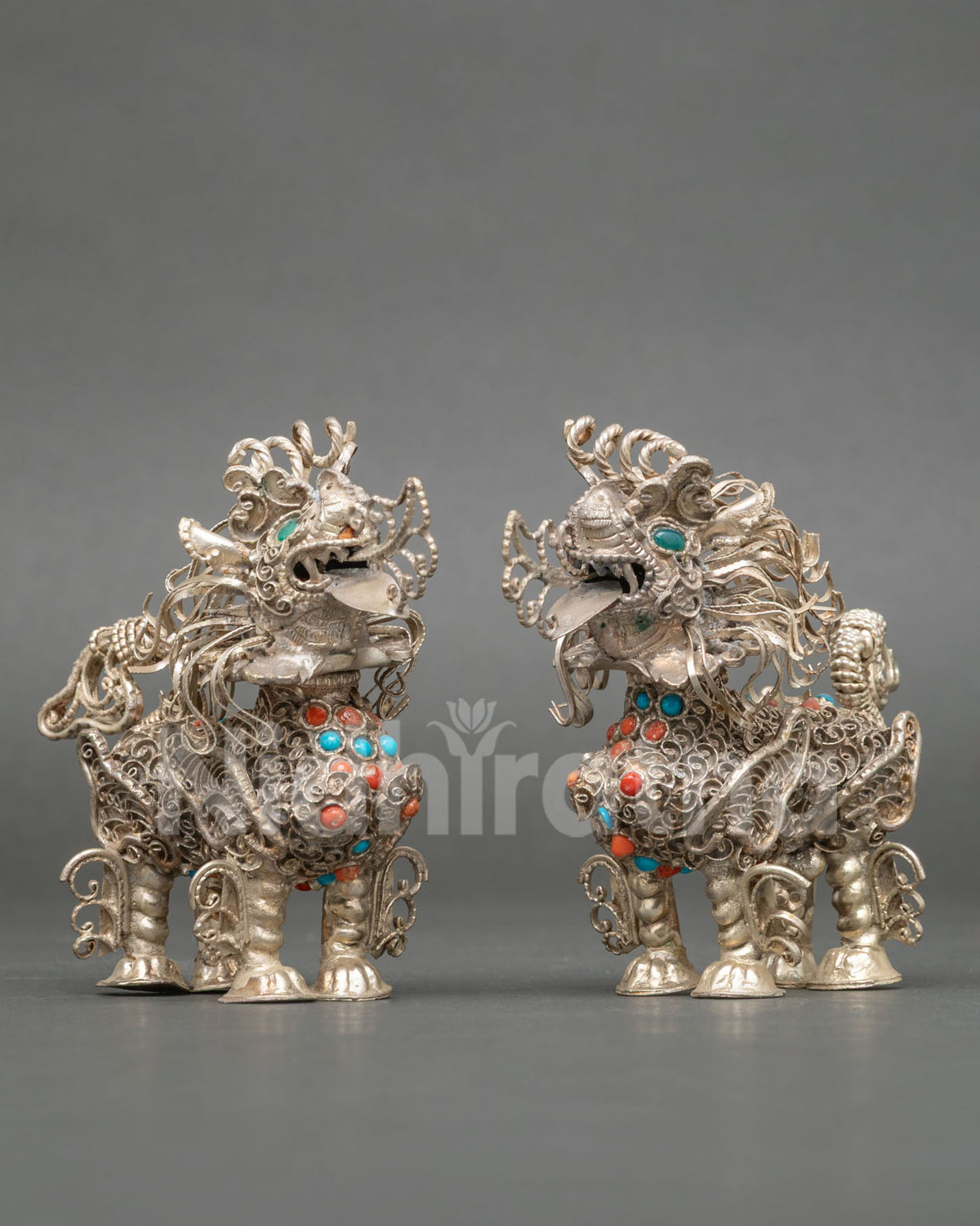 Silver plated Tibetan Snow Lion pair featuring intricate filigree artwork and semi precious stones.