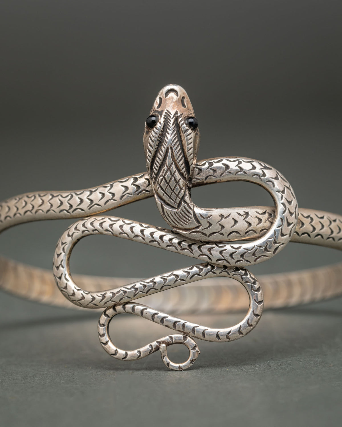 Silver snake bracelet featuring a sculpted serpent head with glossy black eyes