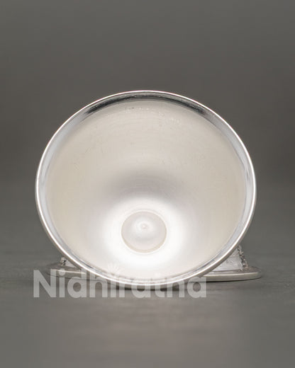 Silver water offering bowl displayed on Tibetan Buddhist meditation altar