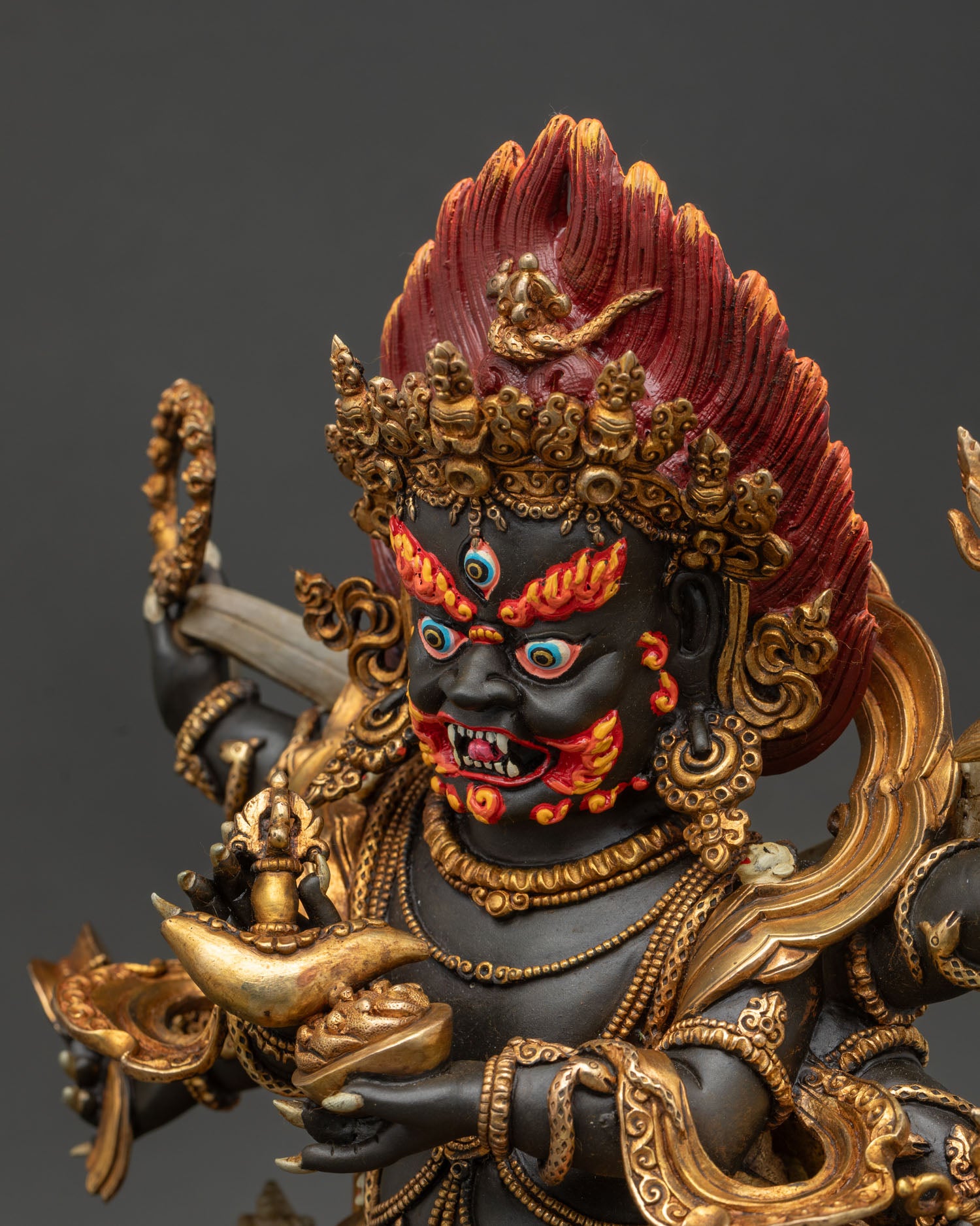 Six-armed Mahakala statue side close-up of the face, emphasizing the third eye, skull crown, and intense wrathful expression.
