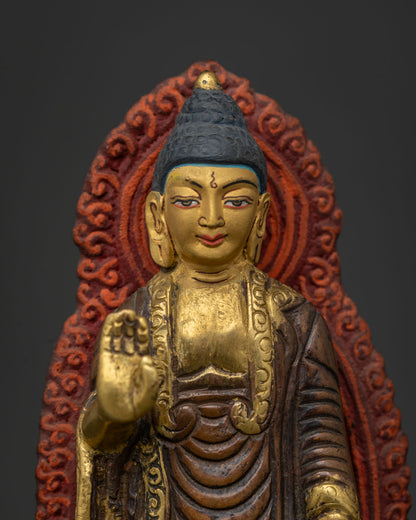 Standing Buddha statue close up gold painted face red gold halo and lotus throne.