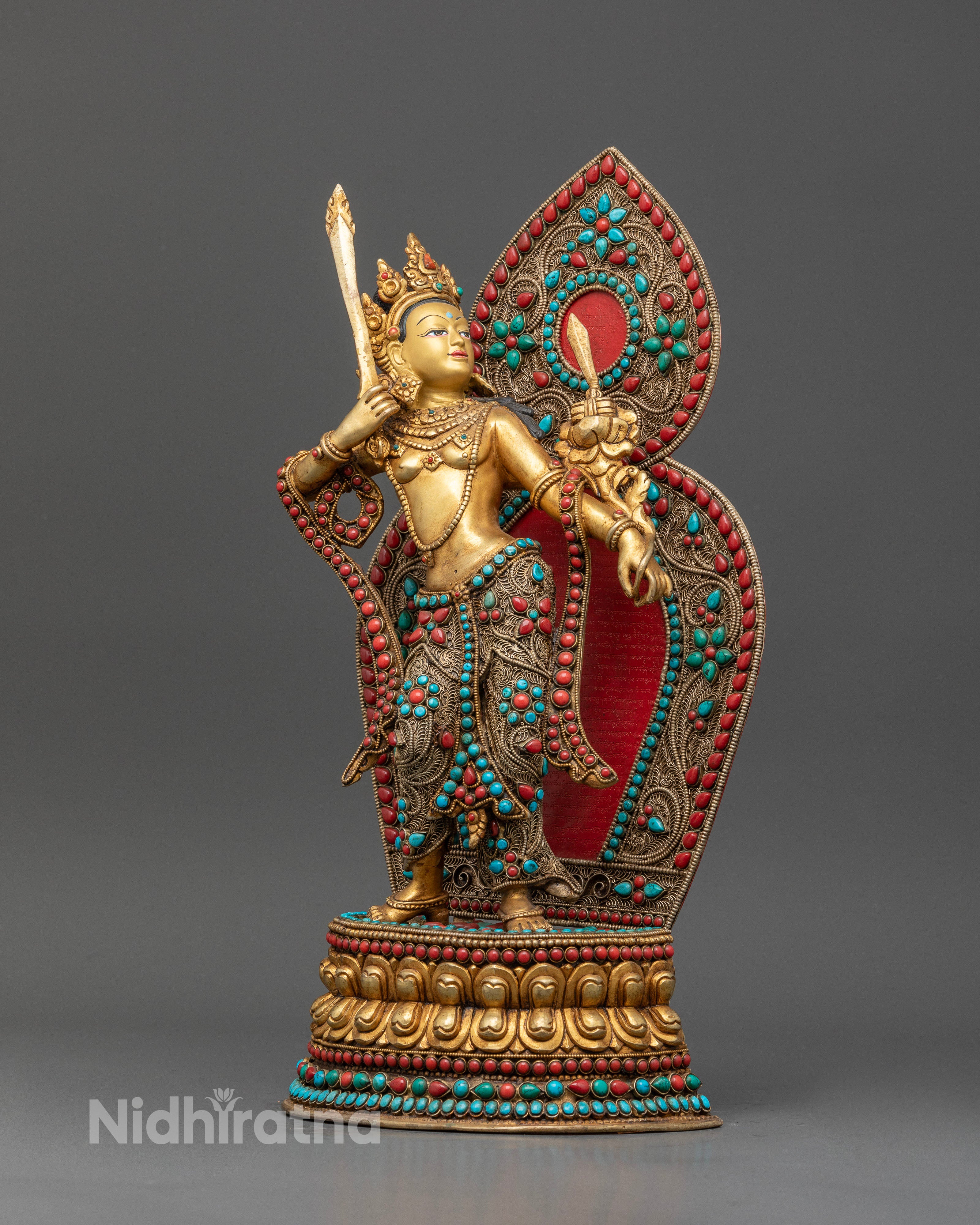 Standing Manjushri statue on double lotus pedestal with ornate halo.