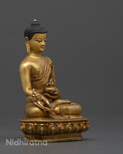 the 24K Gold-Gilded Medicine Buddha Statue, highlighting the detailed carvings on the robe, the myrobalan plant in the left hand, and the vessel of medicinal nectar in the right, with a graceful lotus throne