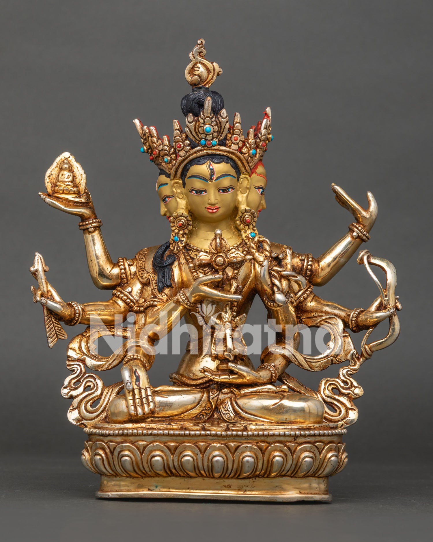 Three faced Namgyalma statue seated on lotus pedestal holding dorje vase and sacred symbols.