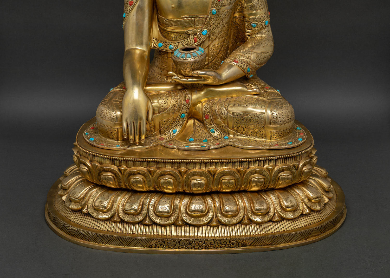 Three-quarter angle of Buddha statue on lotus base with mantra inscription