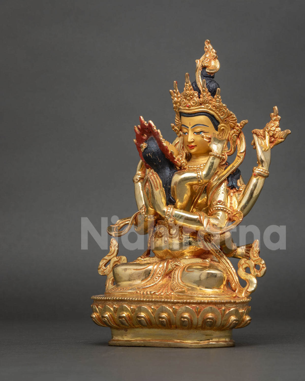 Three-quarter angle view of Chenrezig Yab-Yum statue with red flame halo and gold base