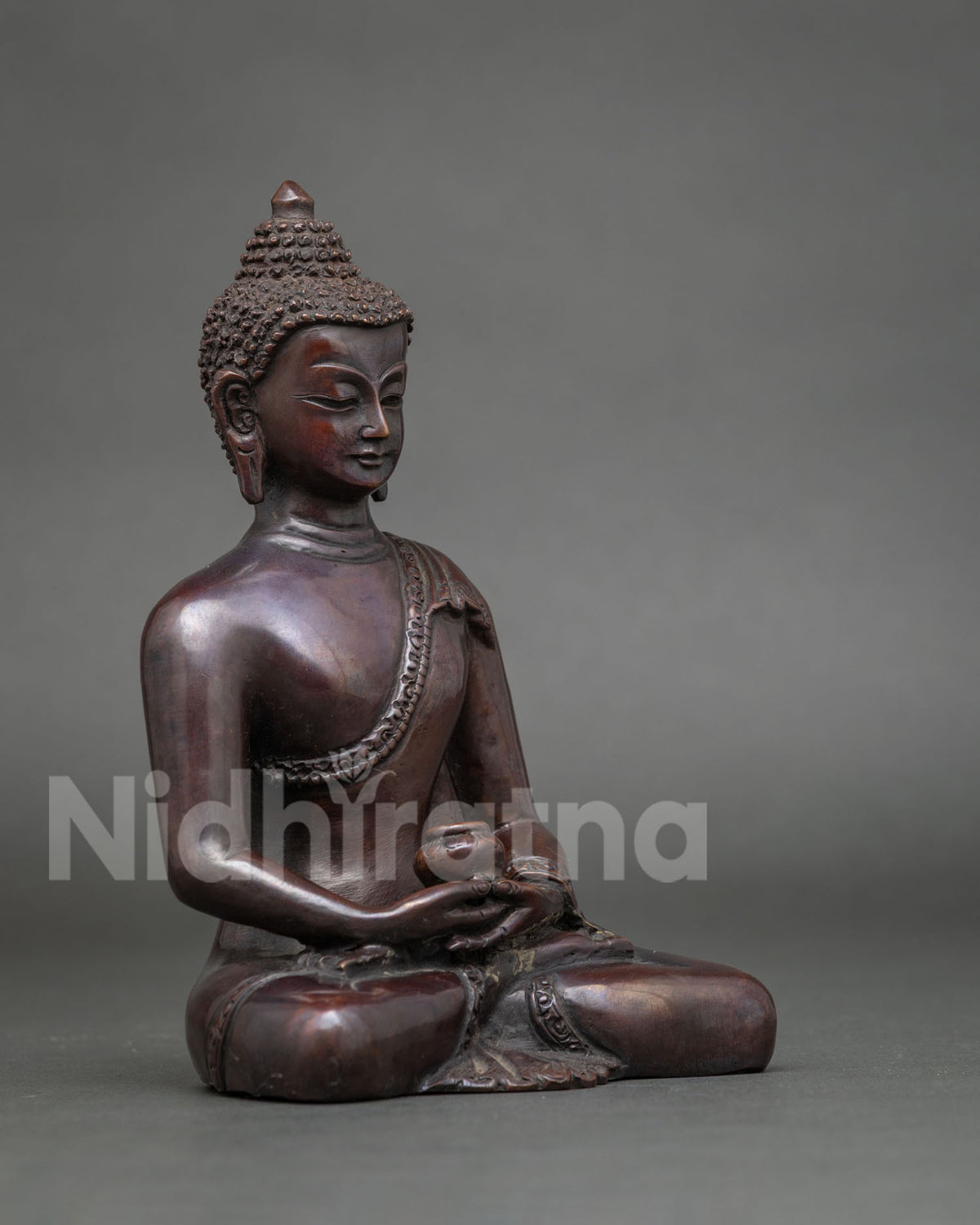 Three-quarter side view of Amitabha Buddha copper statue with oxidized brown finish and alms bowl
