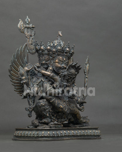 Three-quarter side view of Buddhist Hayagriva bronze statue with antique patina and ritual staff