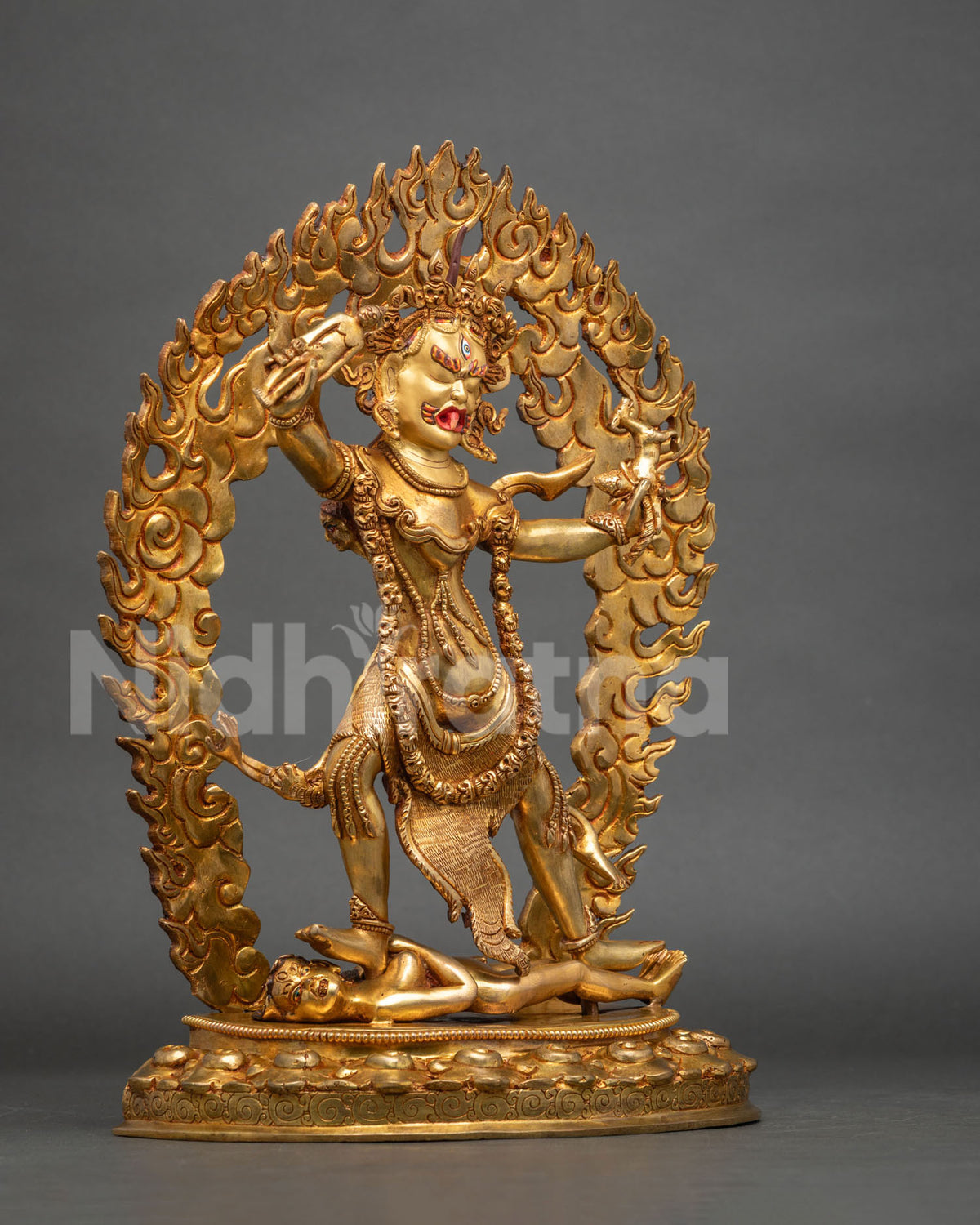 Three-quarter side view of gilded copper Ekajati statue standing on a prone figure