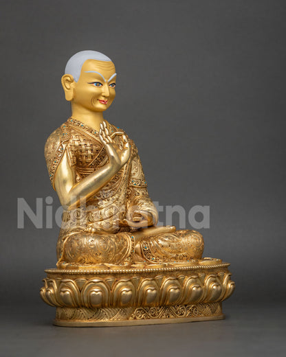 Three-quarter side view of Gyaltsab Je statue with white hair and gold-gilded robe on lotus base