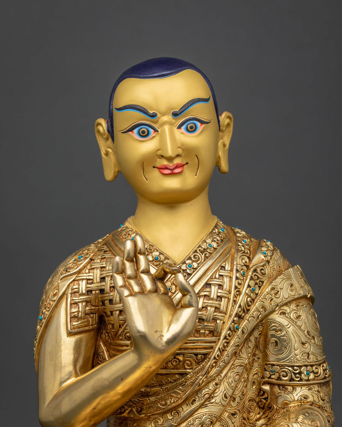 Three-quarter side view of Je Tsongkhapa statue beside lotus stems with sword and book