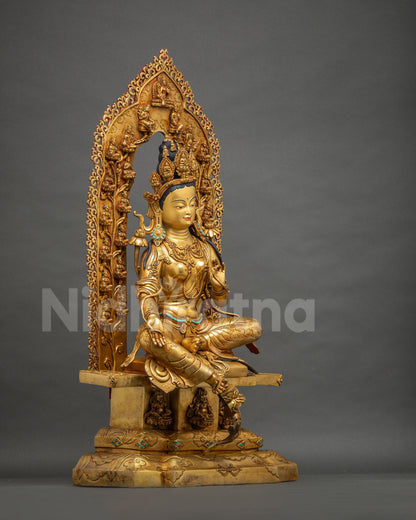 Three-quarter view of Green Tara statue on carved throne with celestial halo and Dzambhala figures