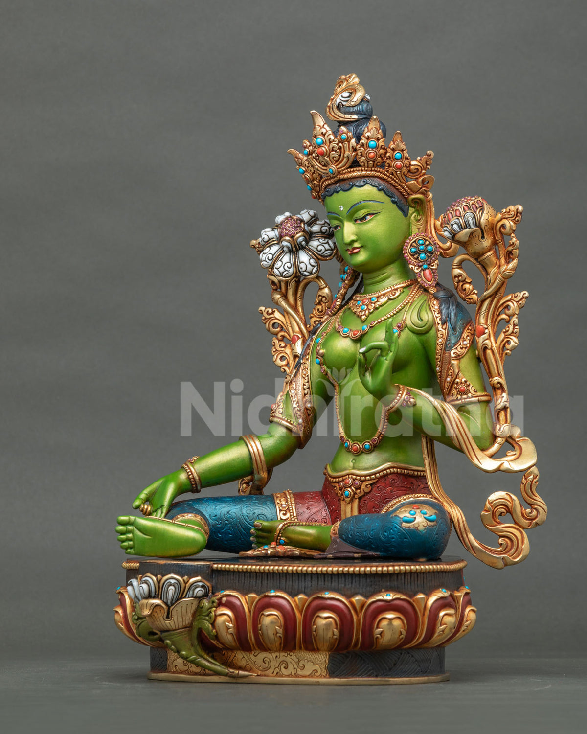 Three-quarter view of seated Green Tara statue showing gold jewelry and red and blue garments