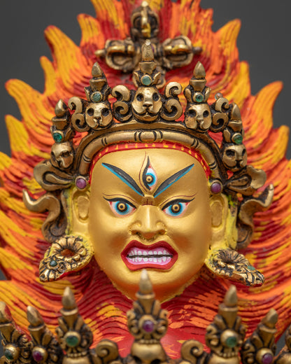 Top wrathful head of Hevajra with flame backdrop, skull crown and vajra, gold fire-gilded finish