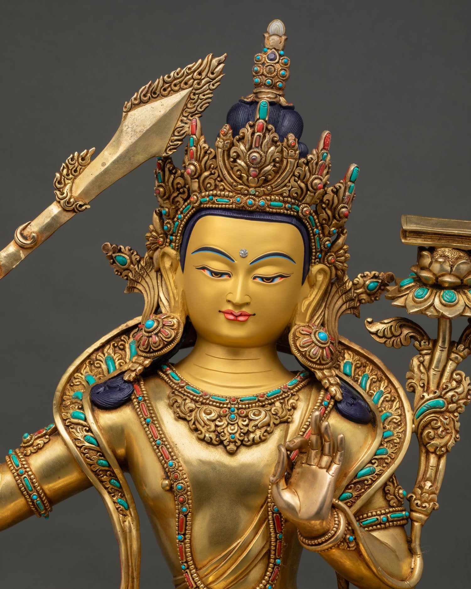 Upper body close-up of gilded Manjushri Statue with jeweled crown and sacred ornaments