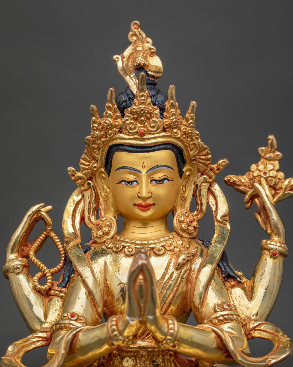 Upper body view of Four-Armed Chenrezig statue with gilded face, crown and prayer hands
