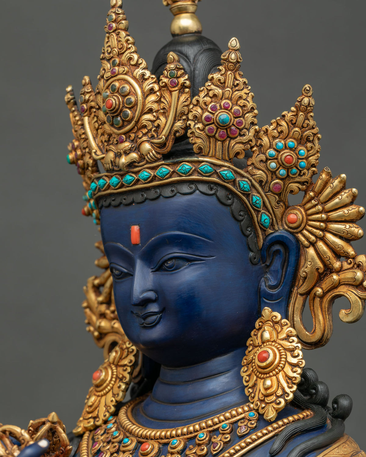 Vajradhara statue face side profile, downcast gaze, gold crown, Newari art