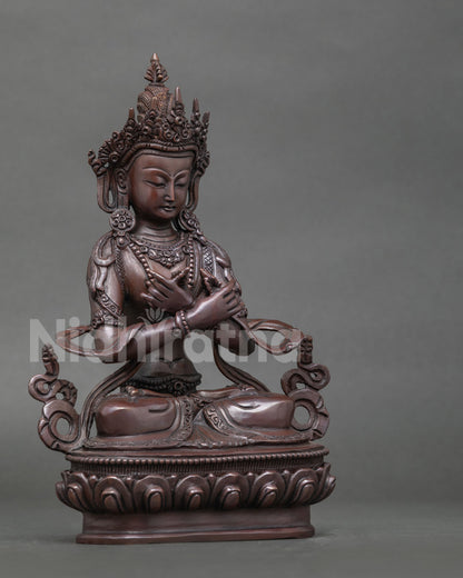 Vajradhara statue seated in vajraparyanka posture on detailed lotus pedestal.
