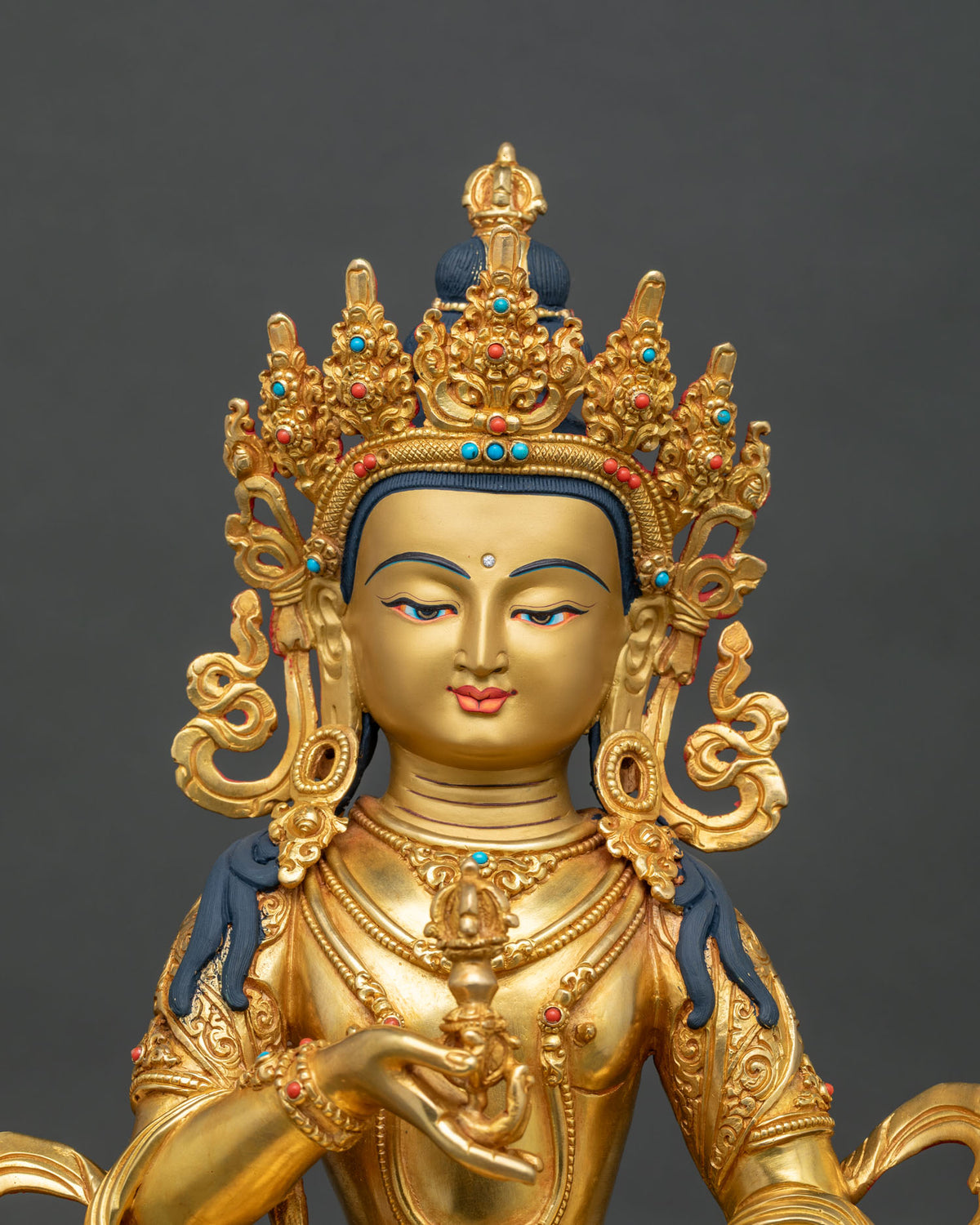 Vajrasattva Buddha statue close up 24K gold painted face semi precious stone jewelry.