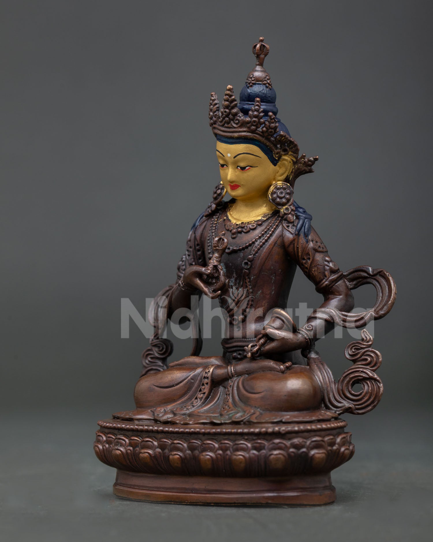 Vajrasattva Buddhist statue seated on lotus pedestal holding vajra and bell with traditional details.