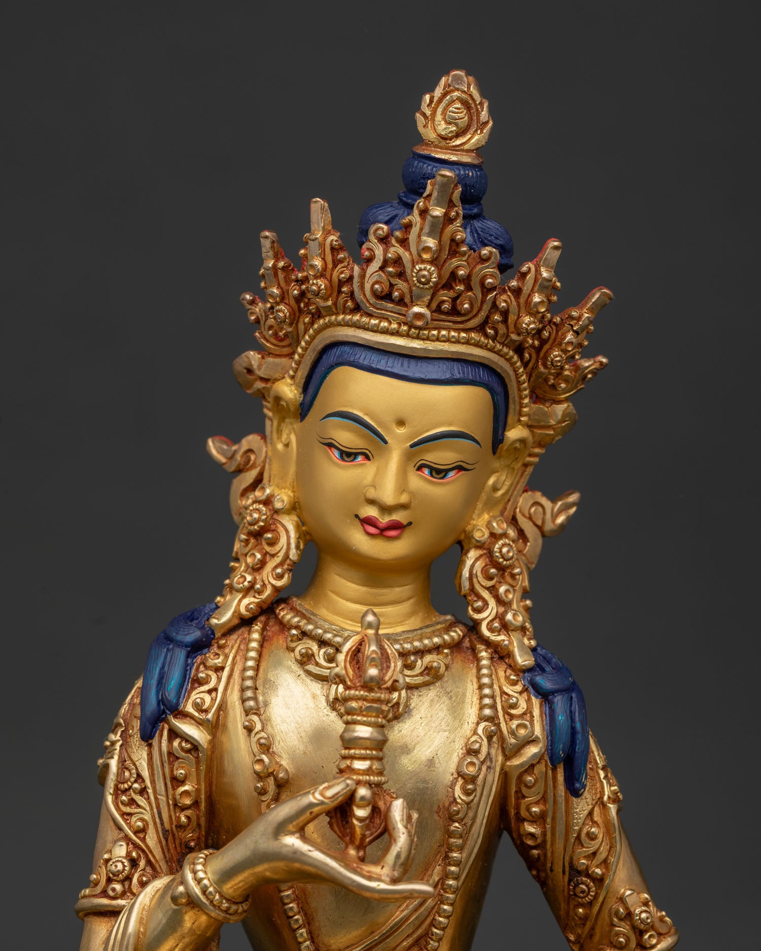Vajrasattva statue close up showing gold painted face and five jewel crown details