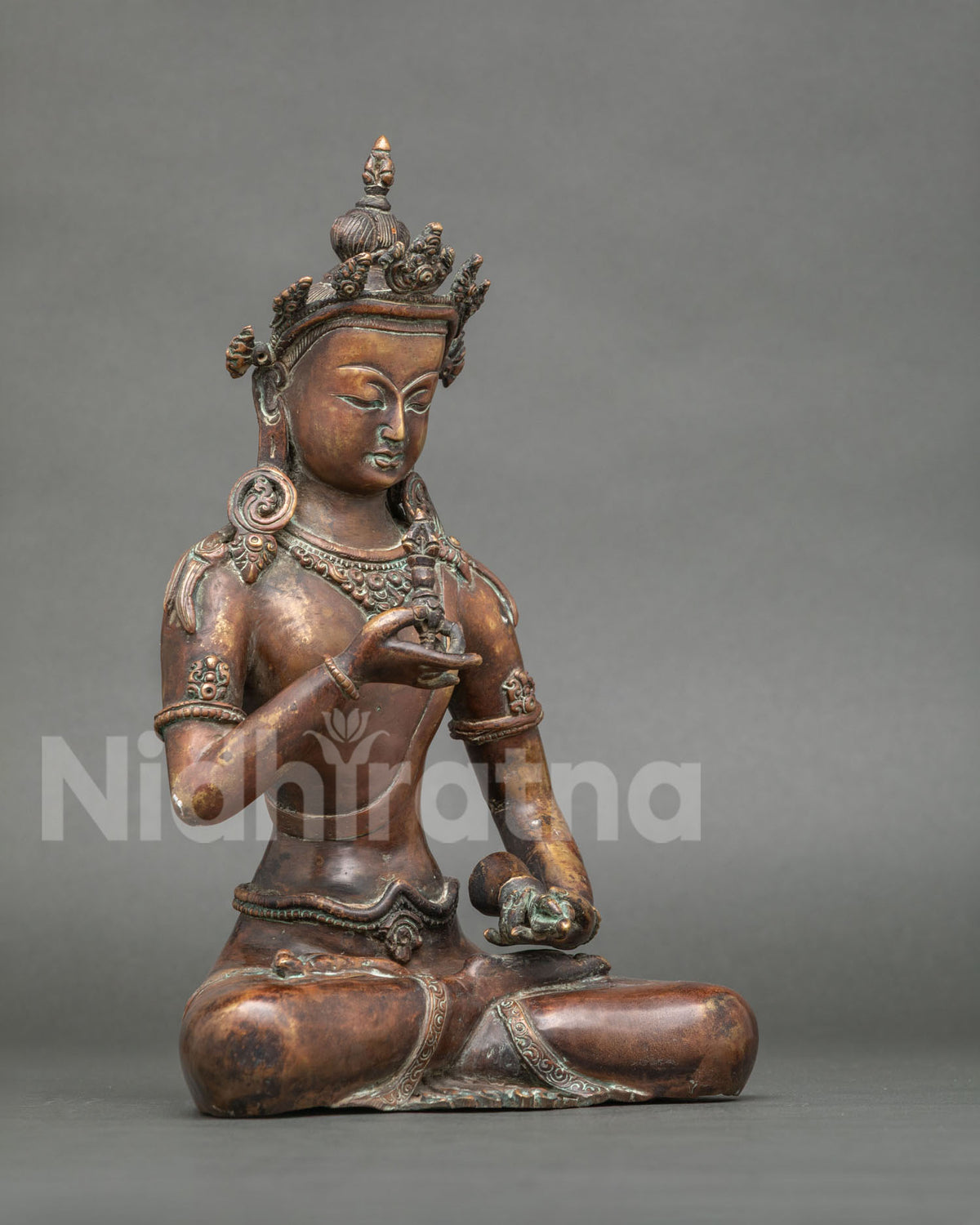 Vajrasattva statue detail five pronged vajra and ritual bell in hands.