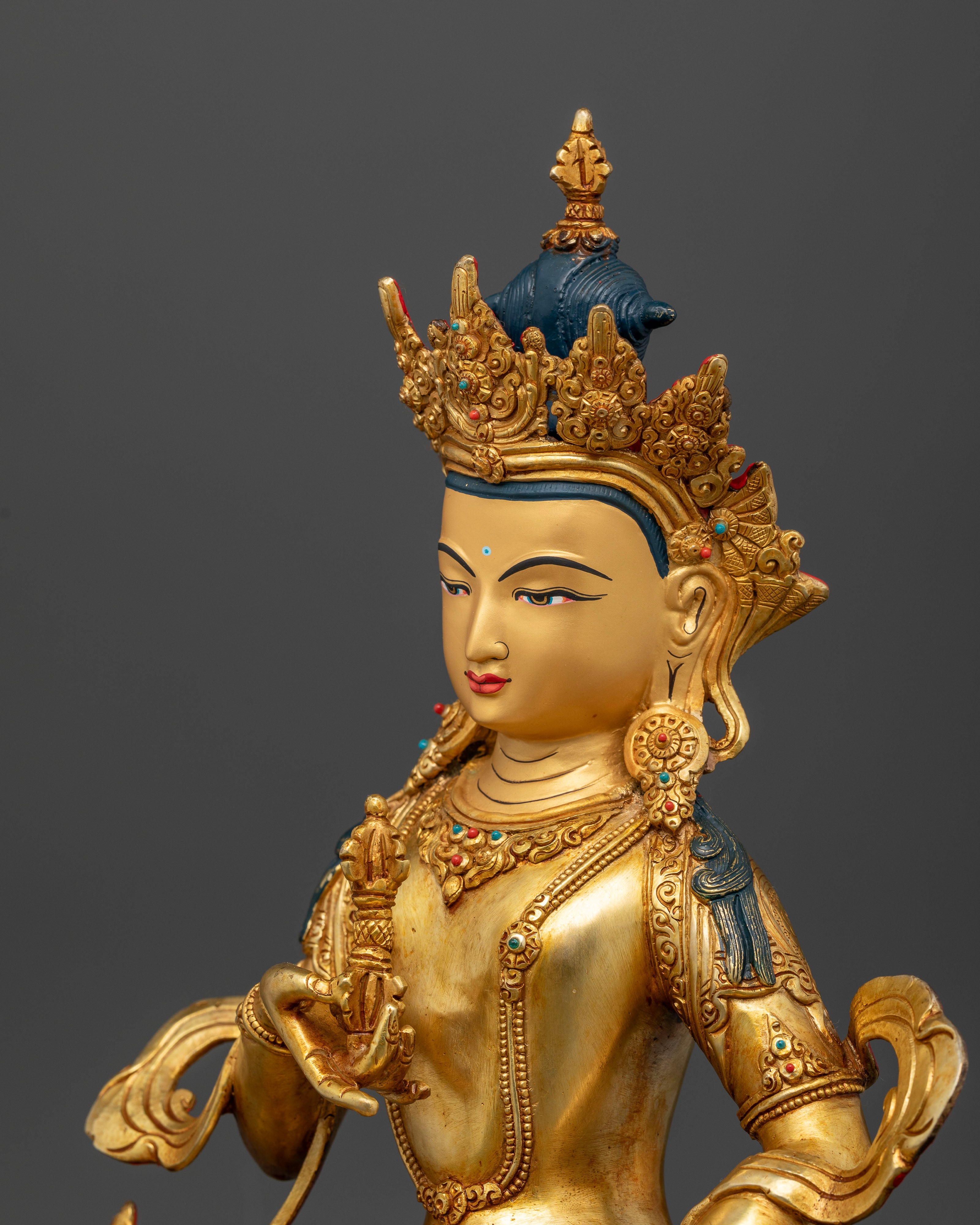 Vajrasattva statue holding vajra and bell adorned with turquoise and coral stones.
